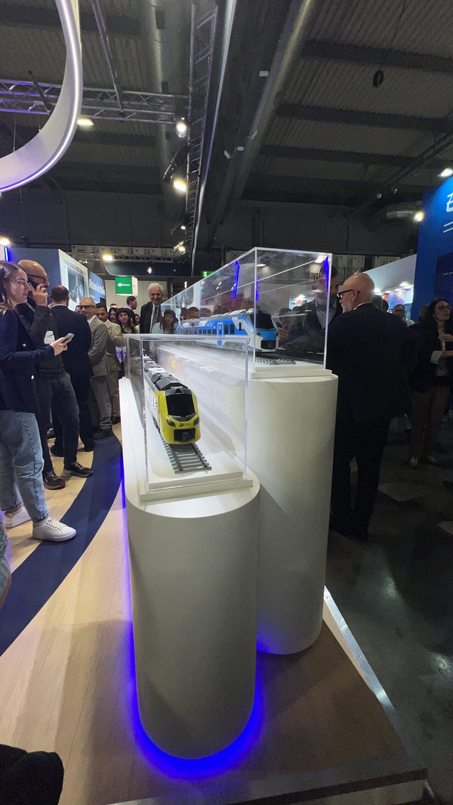 Foto panoramica della Fiera Milano Ferroviaria 2025 con logo Teknotel sovrapposto, oppure immagine dello staff Teknotel in visita agli stand.
